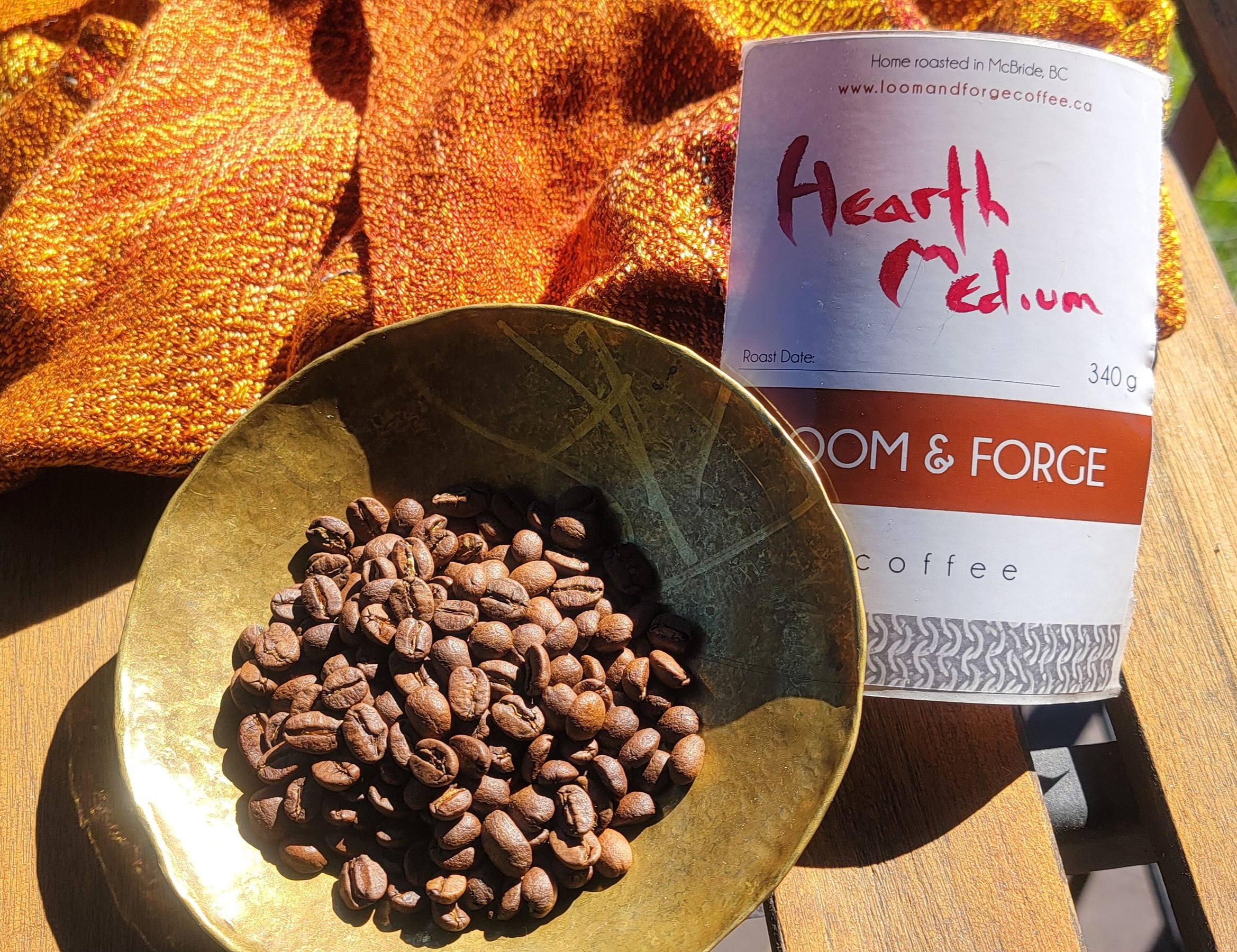 Gold bowl with coffee beans and 'Hearth Medium' coffee package on a wooden surface